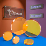 Five ZInc Selenide focusing lenses sit on a blue table. There is an engraved sign that reads "Elitemark" hanging on the wall behind them.