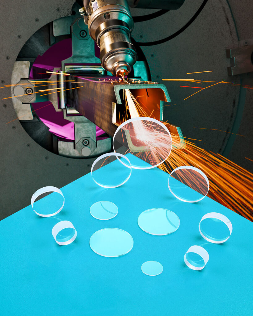 An array of clear spherical laser debris shield sit on a blue table. a photo of a laser cutting metal is in the background.