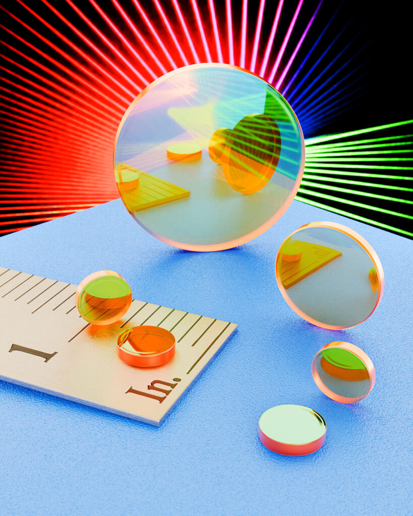 Six Zinc Selenide laser beam splitters sit on a blue table next to a metal ruler showing the smallest to be under an inch in diameter.
