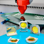 Mounted CO2 laser lenses sit on a blue table. A marking laser is working in the background