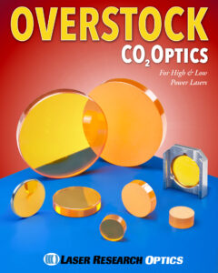 A variety of co2 laser lenses in different sizes and thicknesses are displayed on a blue table with the text "Overstock CO2 Optics" in bold at the top.